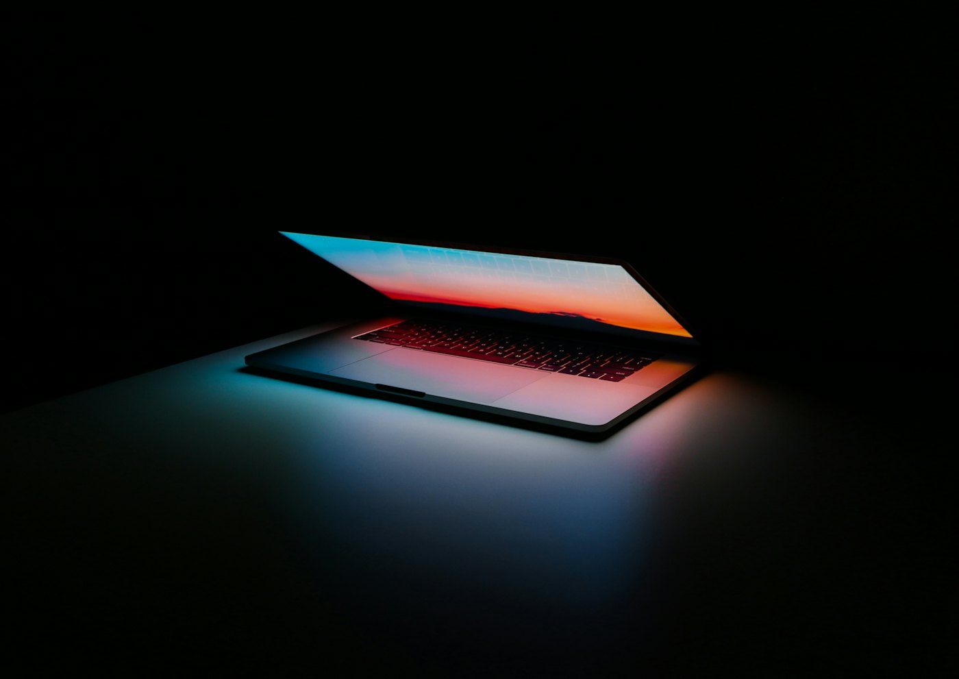 Laptop glowing in a dark room representing cloud-hosted publishing software
