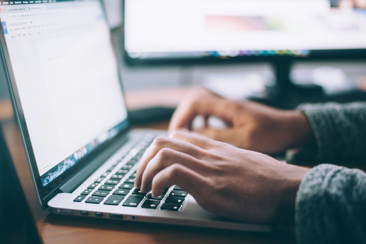 Hands typing on a laptop while uploading a newspaper PDF for conversion to ePaper